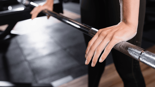 A pair of hands is pressing down on a barbell.