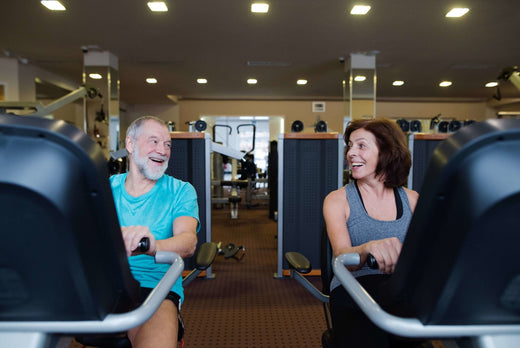 two senior is riding on recumbent exercise bikes and chatting