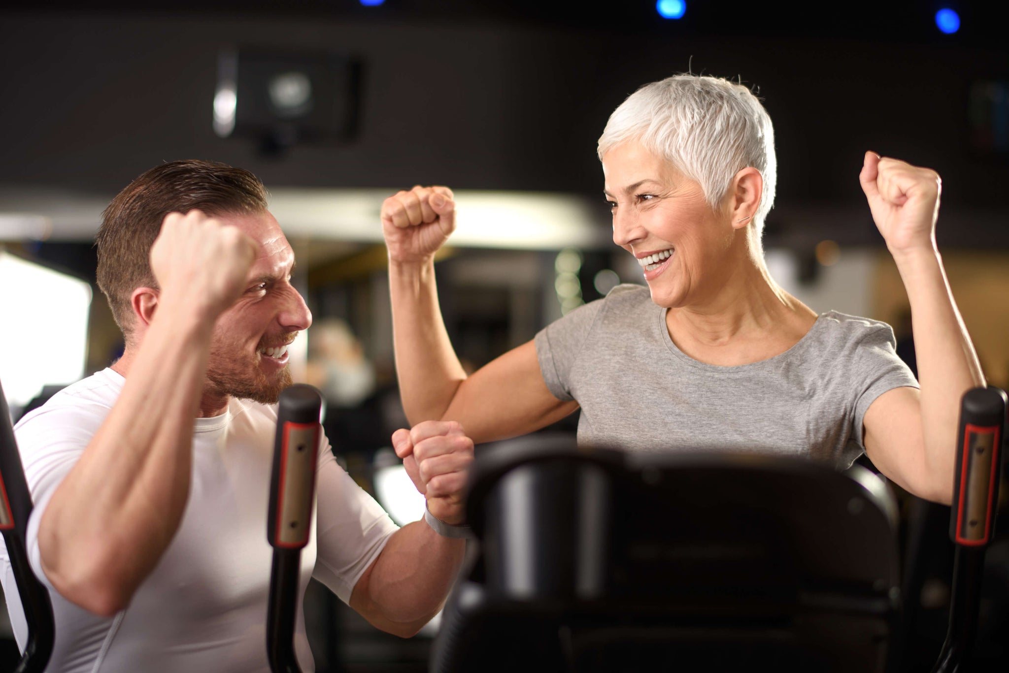 A trainer is coaching an elderly woman on how to exercise on a recumbent bike.